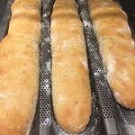 Drei französische Baguette auf einem Baguette Backblech, frisch aus dem Backofen.