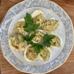 Rezept Gefüllte Eier mit Avocado - Passt auch gut auf das Partybuffet. Auf dem Bild ein Teller mit acht halben, gekochten Eiern, die it einer leckeren Avocadocreme gefüllt sind.