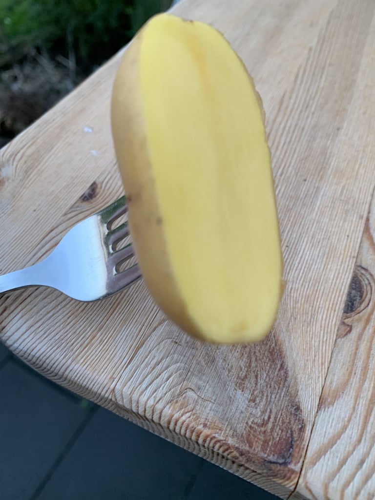 Eine halben Kartoffel auf einer Gabel zum reinigen des Grill Rosts