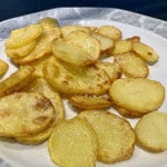 Griechische Knoblauch Kartoffeln auf einem weißen Porzellanteller mit grau gemustertem Rand.