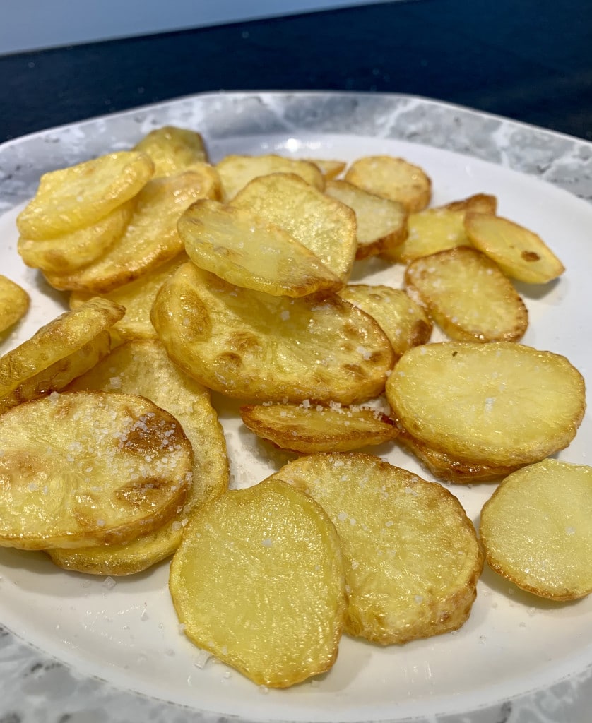 Griechische Knoblauch Kartoffeln auf einem weißen Porzellanteller mit grau gemustertem Rand.