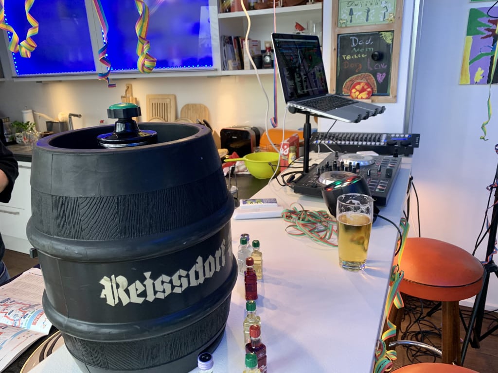 Ein 10 l Fass Kölsch (Pittermännchen) auf einer weißen Küchentheke. Luftschlangen, Mischpult und ein halb volles Kölschglas.