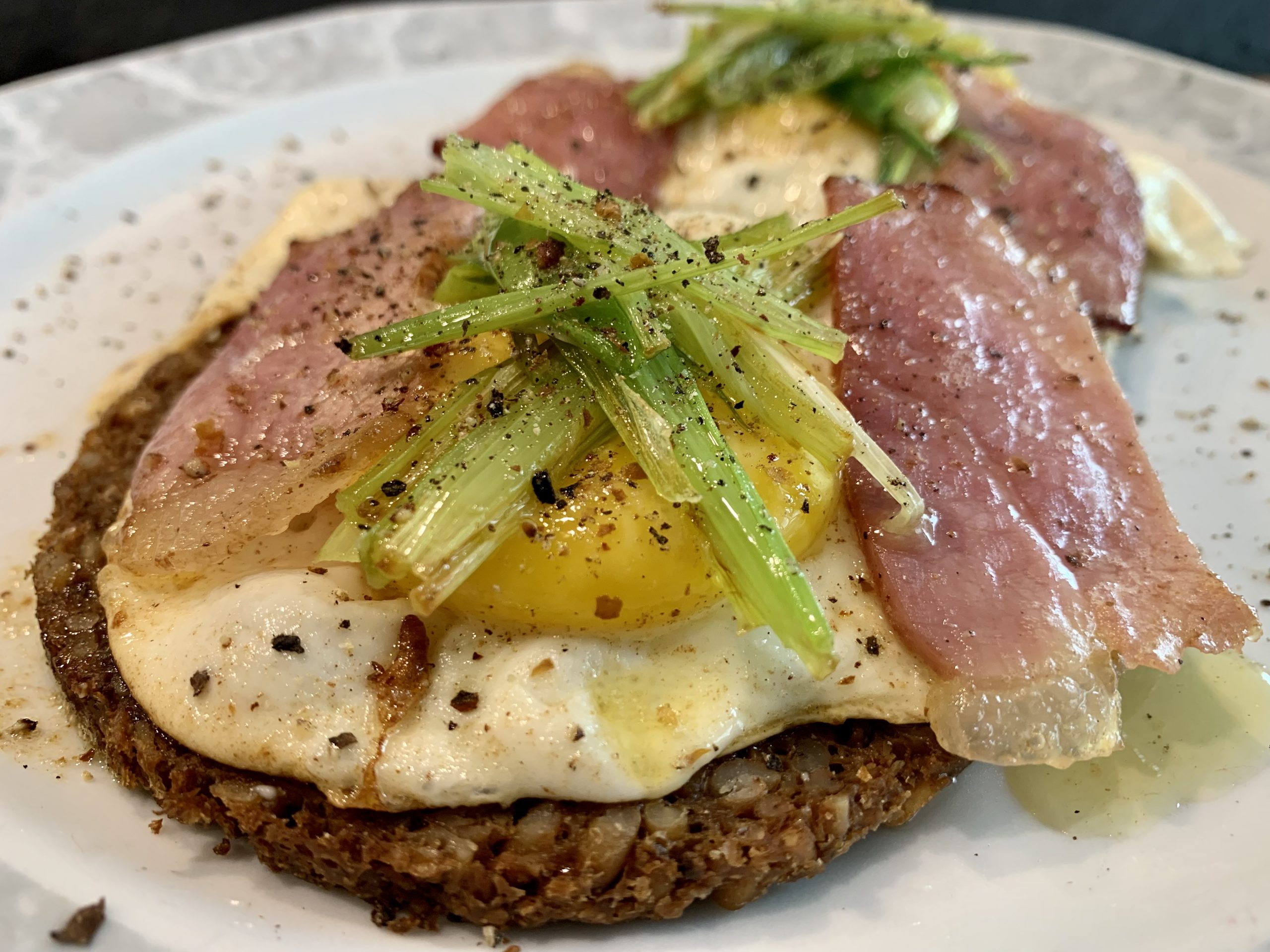 Spiegelei auf Bauernschwarzbrot mit Schwarzwälderschinkenstreifen und angebratenen Frühlingszwiebeln