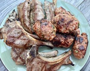 Ein Türkischer Grillteller. Auf einem türkisen Teller liegen gegrillte Lammkoteletts, Lammfilets und Köfte.