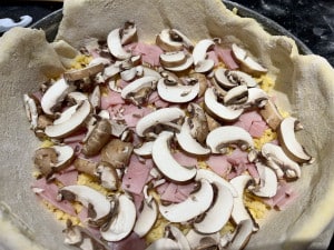 Pilze und Schinken darüber streuen