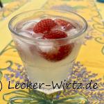 Ein Wodka Gimlet mit Erdbeeren in einem Glas mit Eiswürfel auf einem Tisch mit gelber Decke und Lavendelmuster.