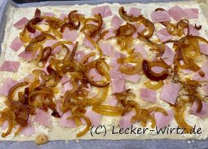 Zwiebeln und Schinken auf dem Flammkuchen verteilen