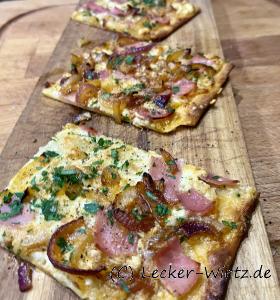 Flammkuchen mit Zwiebeln und Schinken auf Holzbrett
