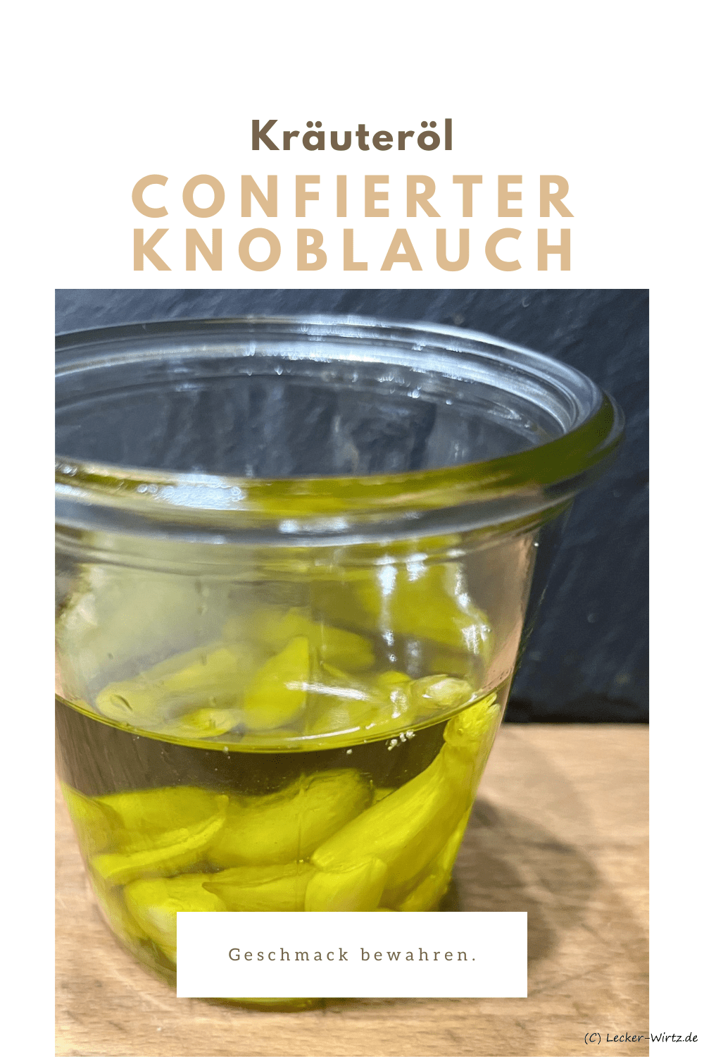 Ein kleines Weckglas mit confiertem Knoblauch auf einer Holzplatte vor einer Schiefertafel.