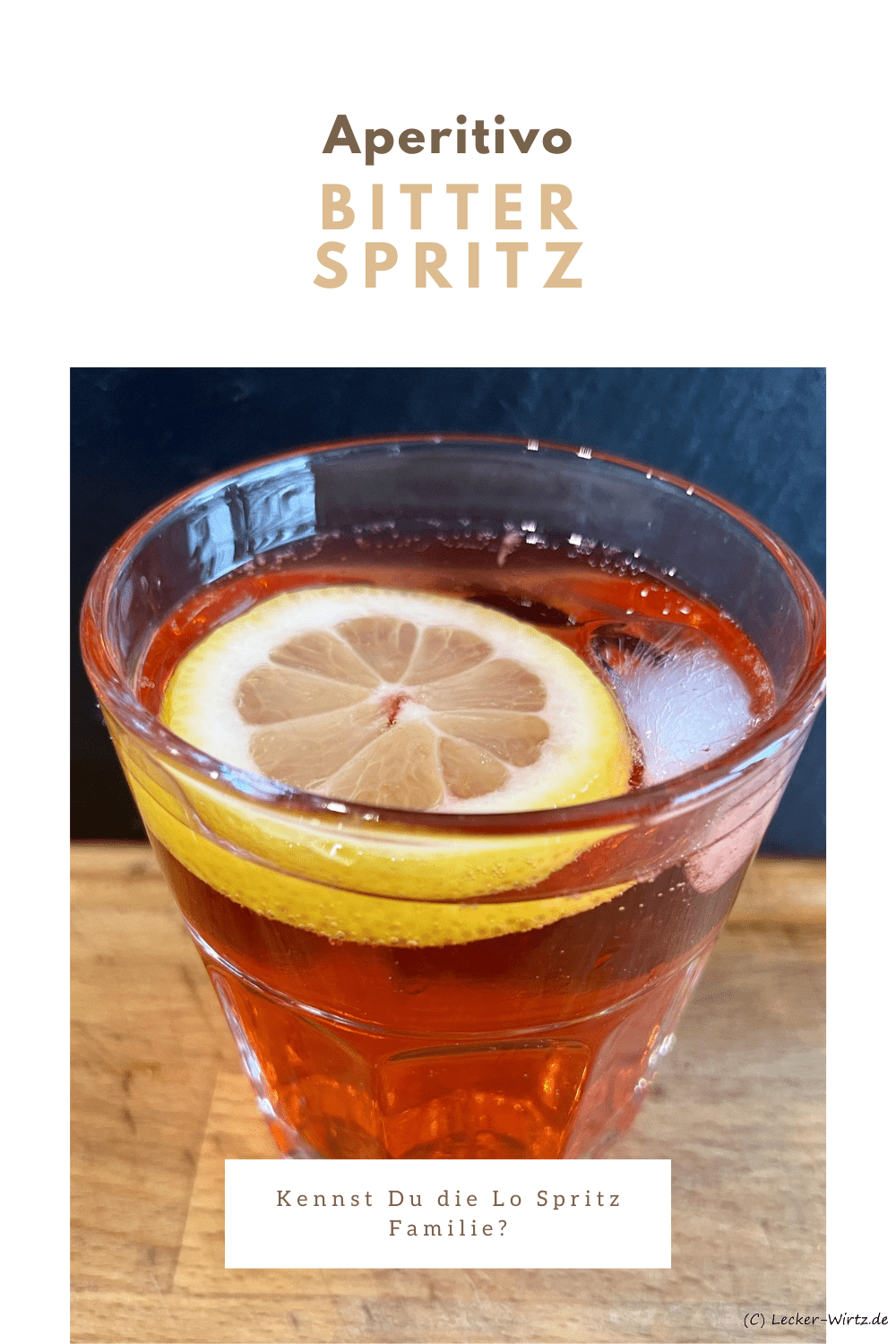 Ein Glas mit Bitter Spritz und Zitrone auf einem Holzbrett vor einer Schiefertafel.