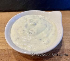 Eine kleine Schale mit Sesam Dressing auf einem Holzbrett.