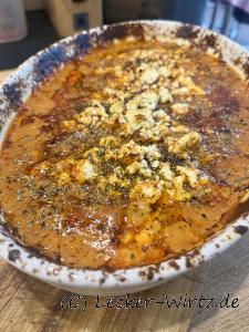 Eine Auflaufform mit Cevapcici in Metaxasauce frisch aus dem Backofen.