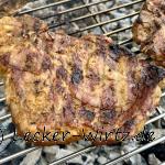 Ein marinierte Nackenkotelettsauf einem Schwenkgrillrost über Holzkohleglut.