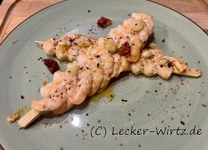 Zwei Garnelenspieße als Fingerfood auf einem pastell-grünem Teller