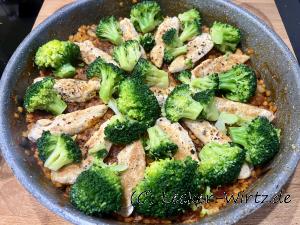 Eine Pfanne mit Hühnchengeschnetzeltes mit Linsen und Brokkoli, Auf den gekochten Linsen liegen die gebratenen Hähnchenstreifen und darüber der knackig-grün gekochte Brokkoli.