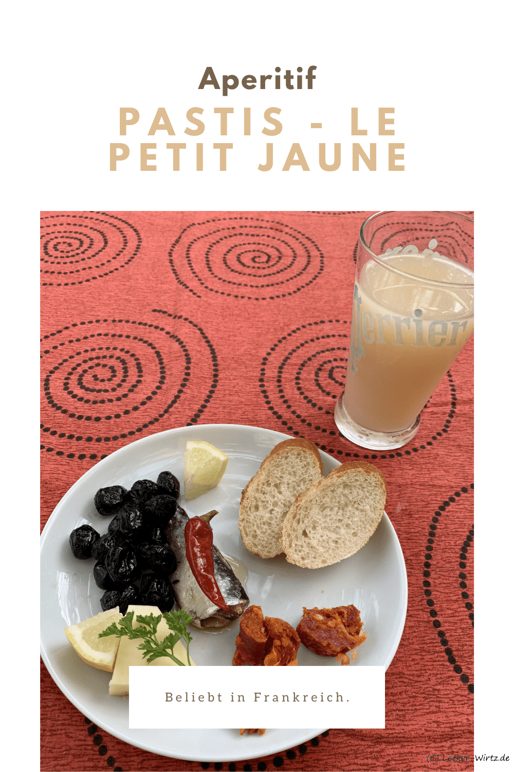 Ein Apero Teller mit kleinen Häppchen und etwas Brot. Daneben ein Glas mit Pastis und Wasser.