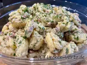 Ein Pfälzer Grumbeersalat (Kartoffelsalat) mit Speck, gehackter Petersilie und Zwiebelstückchen in einer Glasschale.